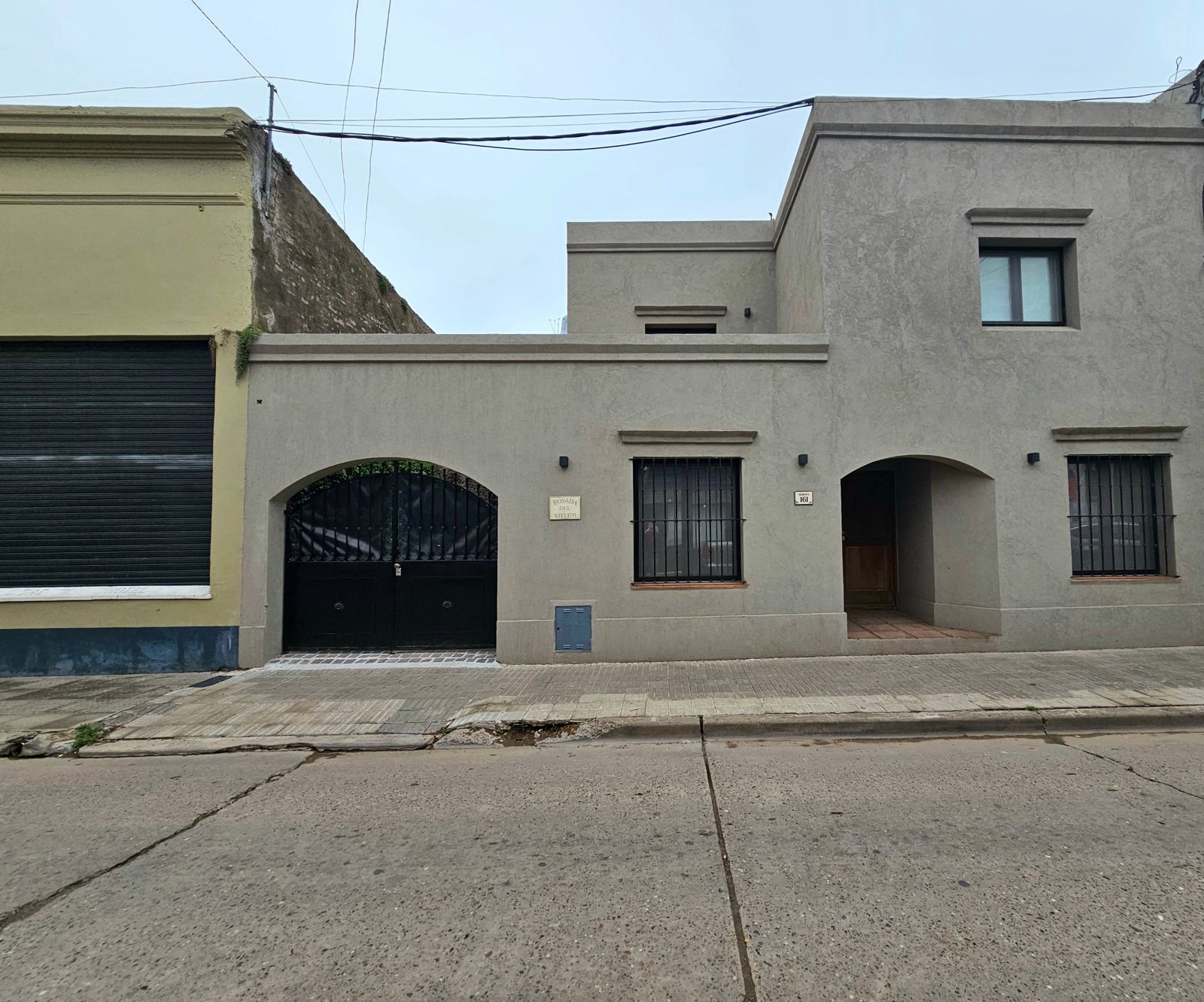 Fachada de la posada sobre la calle Alsina, con portón en arco y rejas negras