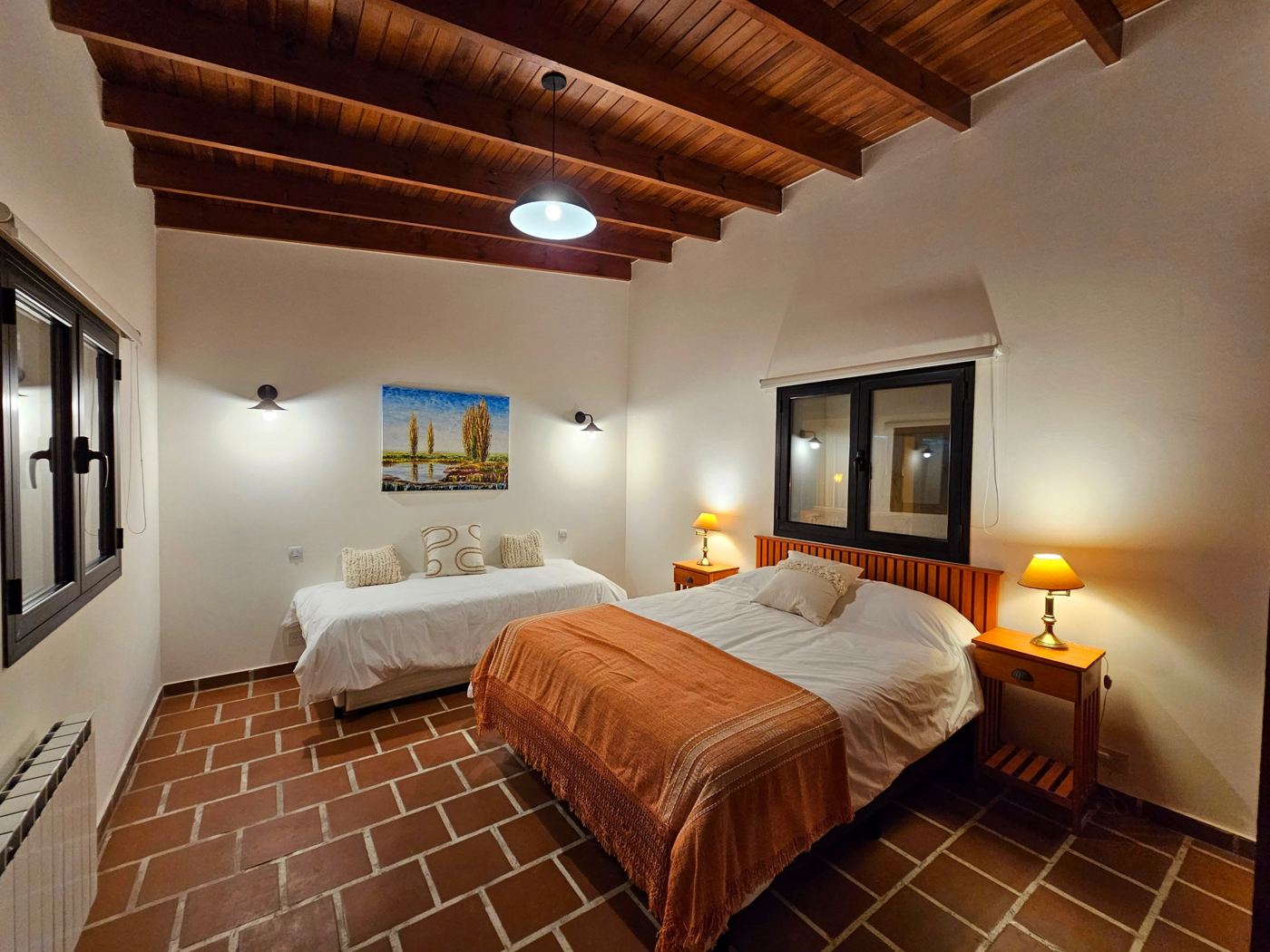 Dormitorio con cama matrimonial, cama individual y techo de vigas de madera